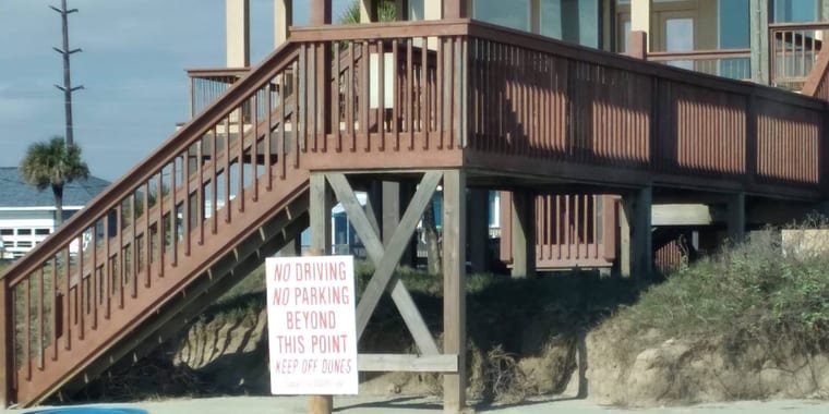 Stained wood stairs and deck railings on a raised beach house