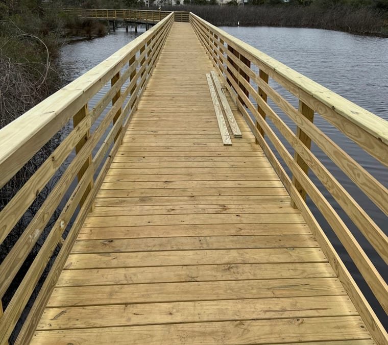 Pressure-treated boardwalk with wood railings crossing open water