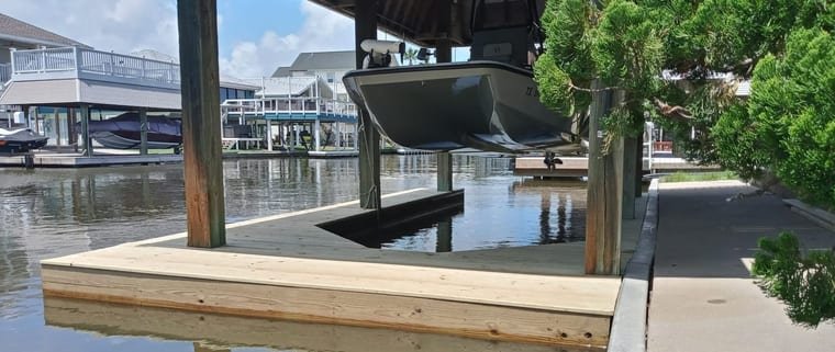 New pressure-treated dock decking beneath a covered boat lift on a canal
