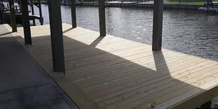 New pressure-treated dock decking along a residential canal