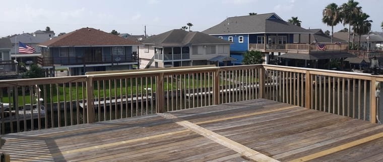 Deck with new pressure-treated railings overlooking canal-front homes
