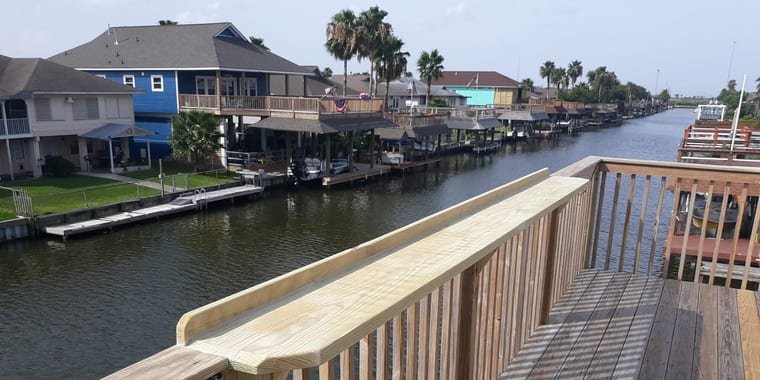 New pressure-treated drink rail on a deck railing above a canal