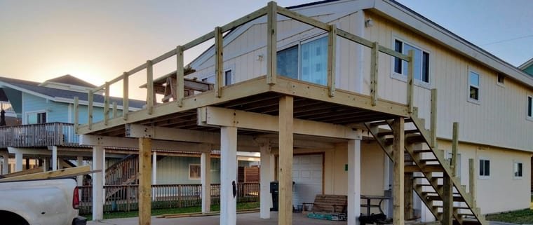 Pressure-treated deck framing, posts and stairs going up on a raised home